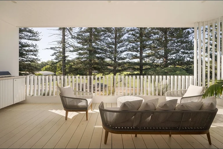 Swanbourne home — upper balcony with outdoor lounge, Norfolk pines beyond